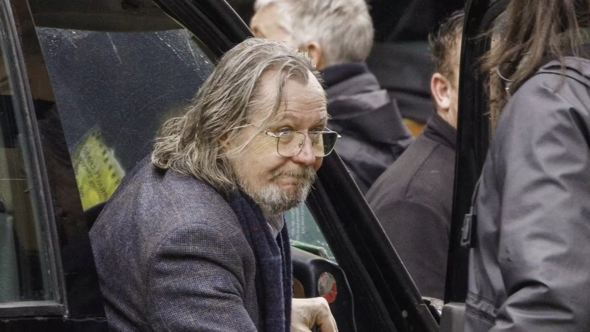 Gary Oldman alighting from a cab in the rain
