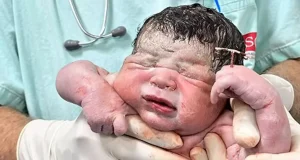Newborn baby holds contraceptive coil Newborn baby holds contraceptive coil