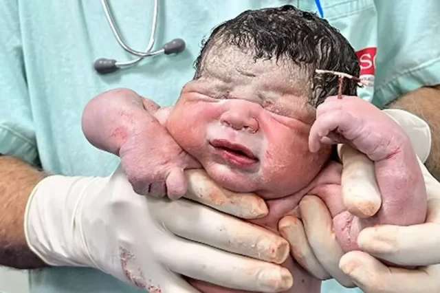 Newborn baby holds contraceptive coil Newborn baby holds contraceptive coil